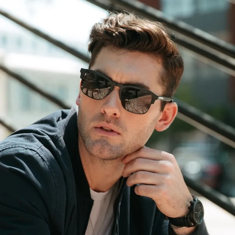 Man in a dark jacket and sunglasses photographed outdoors for a fashion campaign