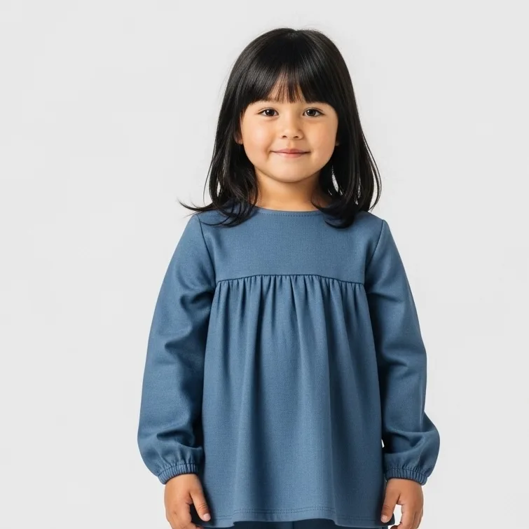 Young girl wearing a blue long sleeve gathered blouse on a plain background