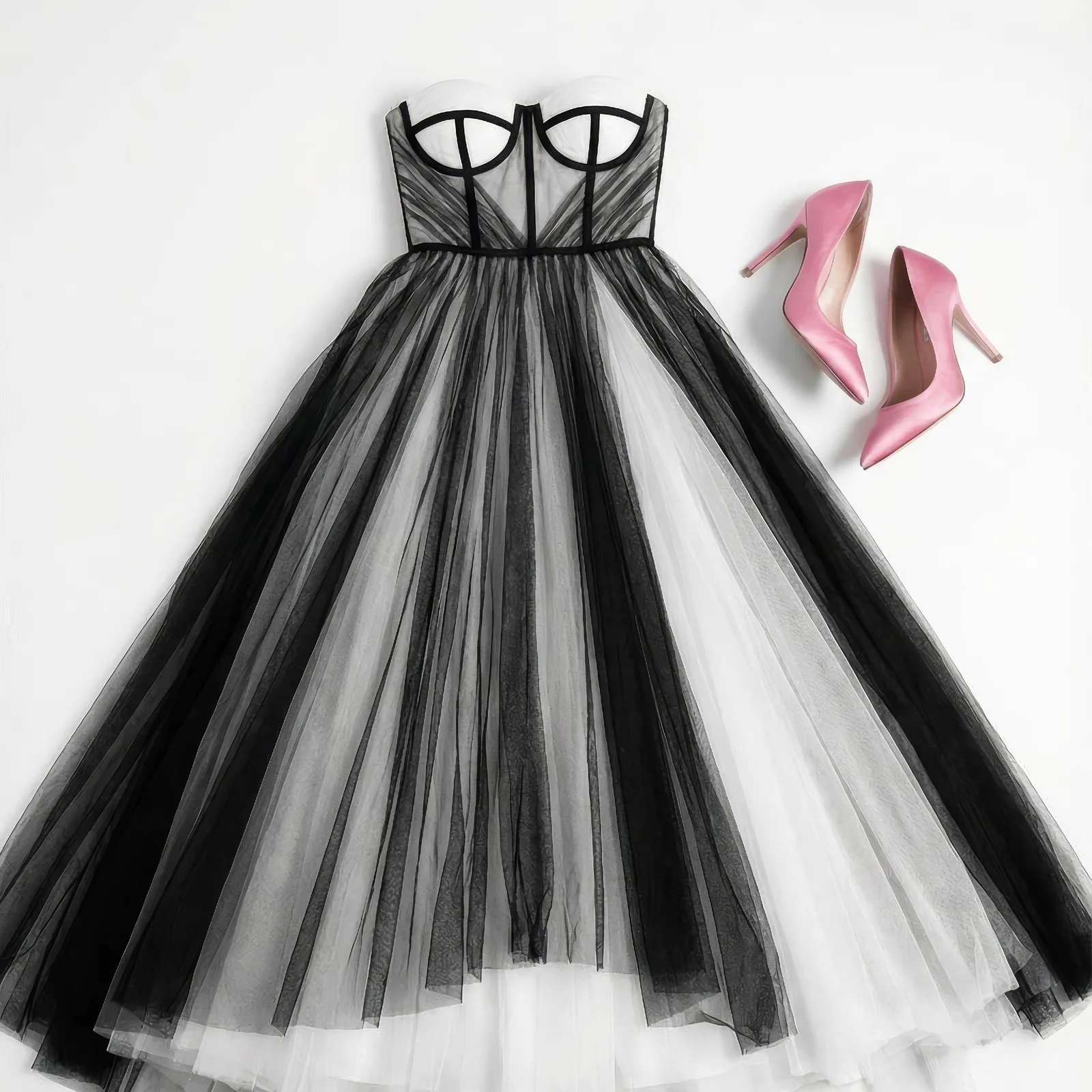 Flat lay of a black and white tulle corset gown with pink satin heels