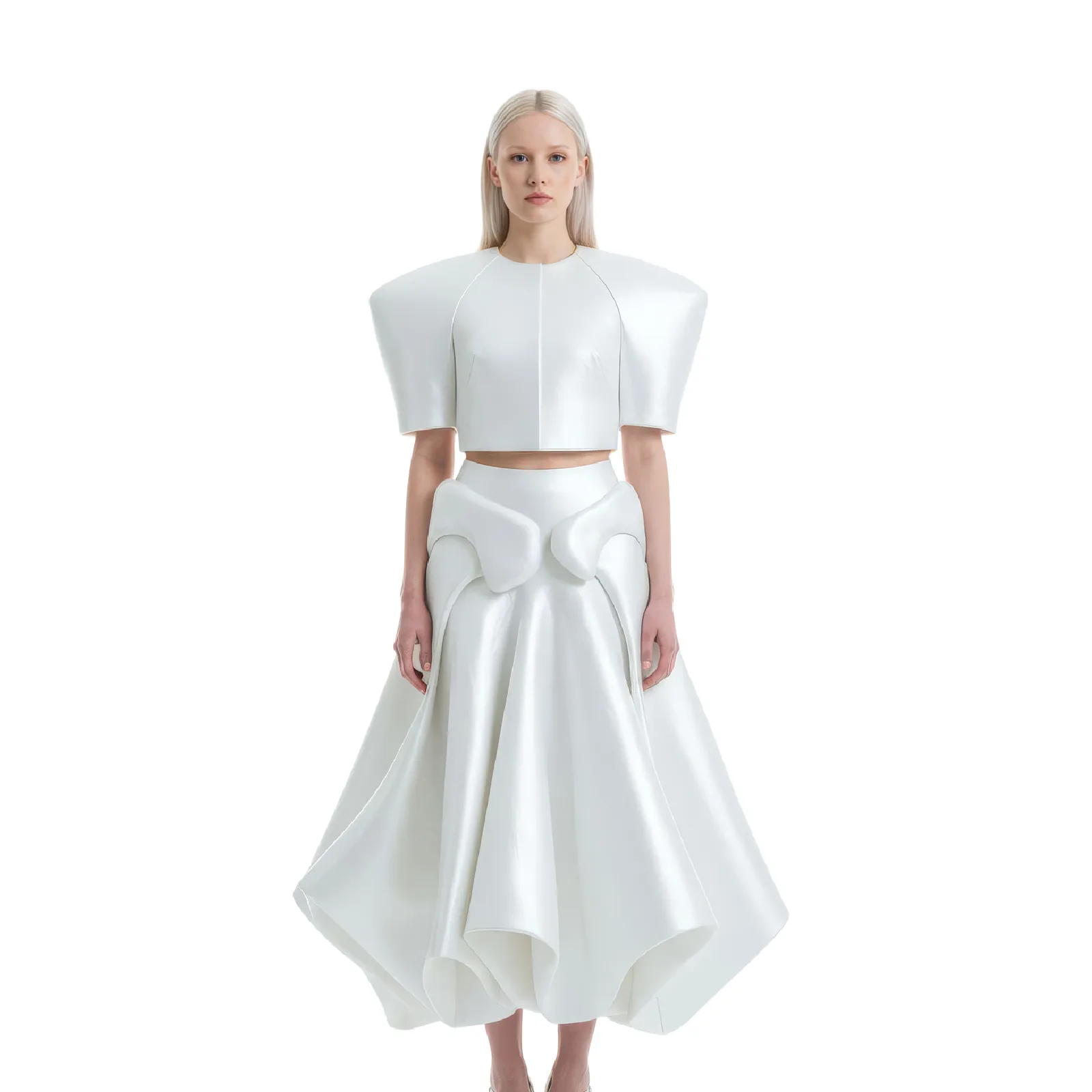 Model in a white structured crop top and sculptural flared skirt with strong pointed shoulders