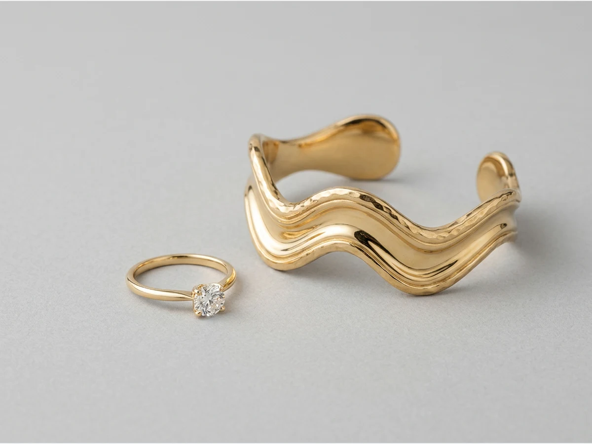 a fine gold ring set with a single stone, product shot, a second design, a sculptural gold cuff bracelet