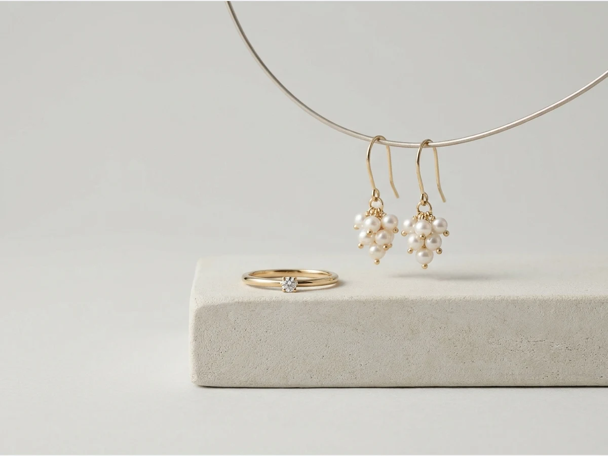 a fine gold ring set with a single stone, product shot, a third design, drop earrings in gold and pearl