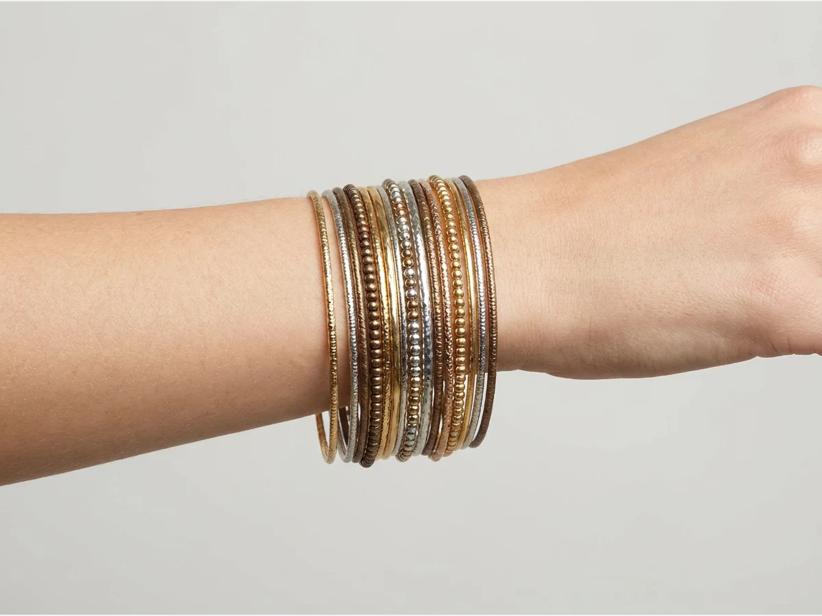 a close shot of a wrist wearing a bracelet, stacked thin bangles