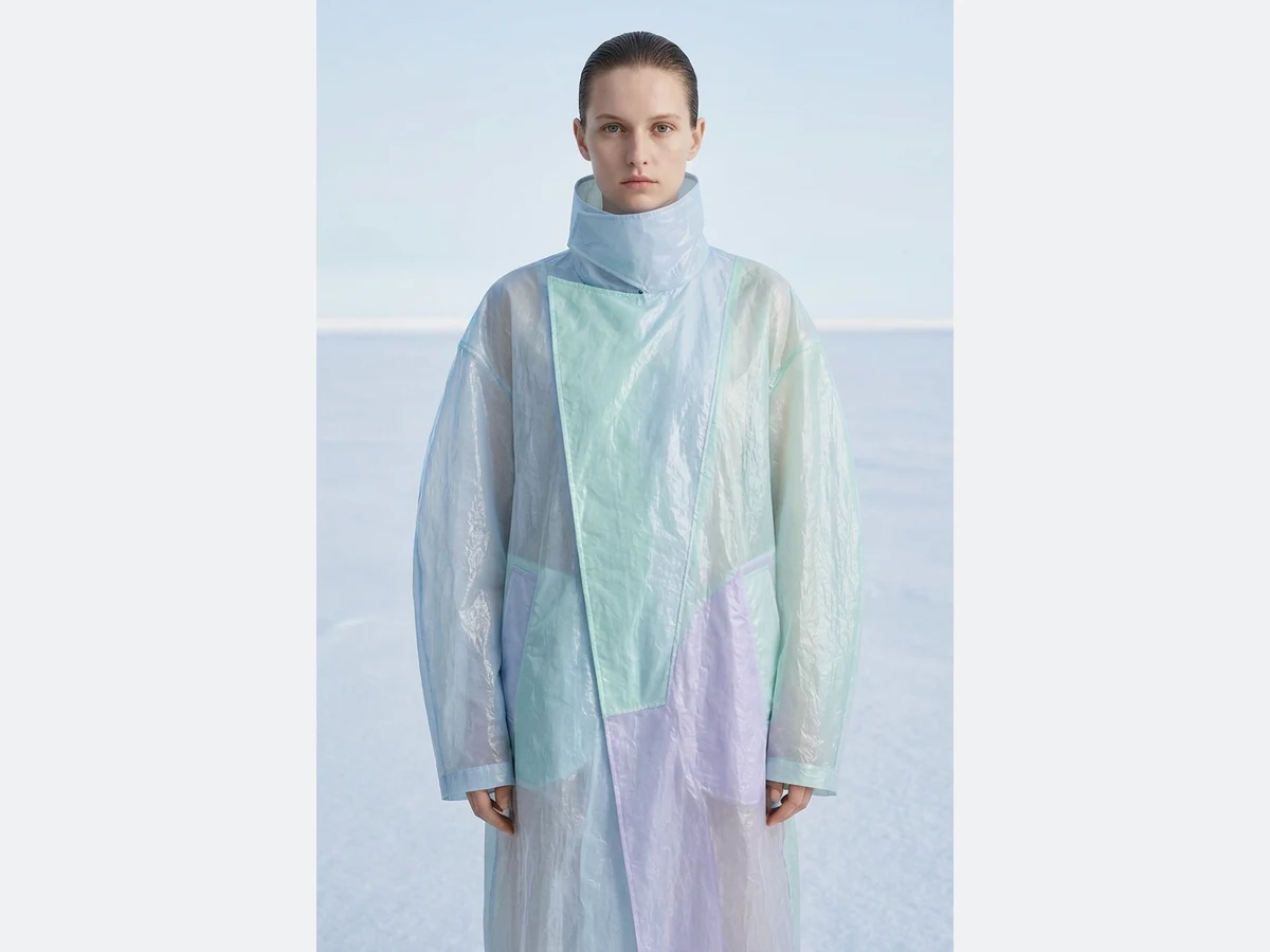 The same model, the same coat, the same pose, standing on a salt flat under an open sky