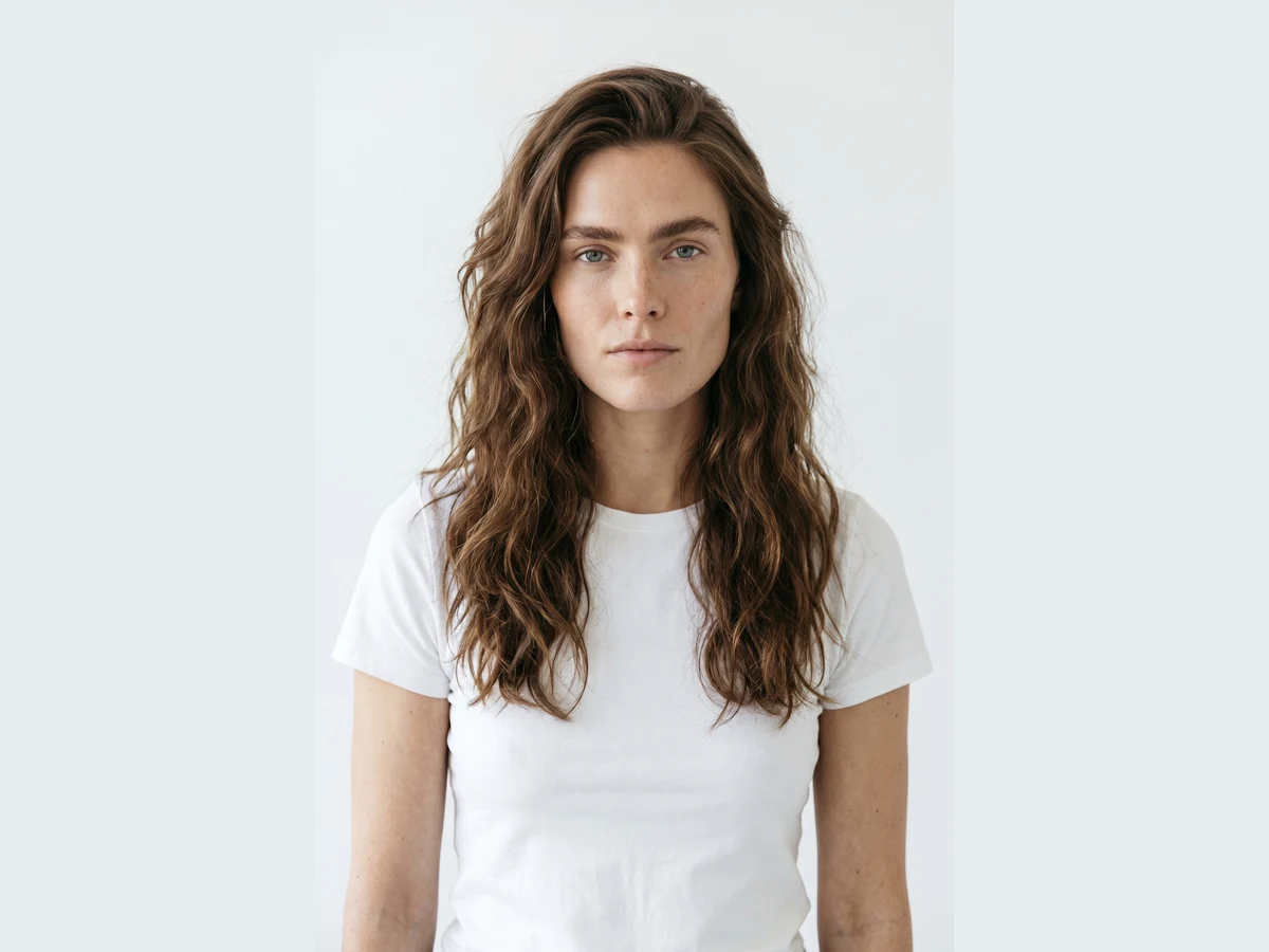A model photographed in a plain white t-shirt against a pale studio wall, the photo used as the try on input